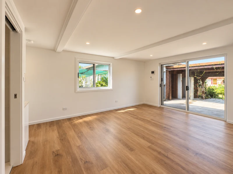 Spacious converted room with timber flooring and sliding garden doors