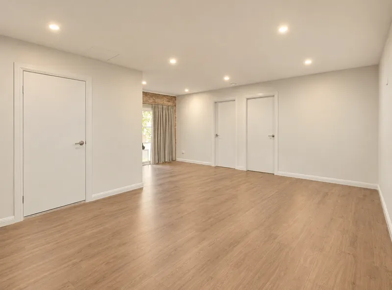 Abbotsbury garage conversion with timber-look flooring, white doors and recessed lighting
