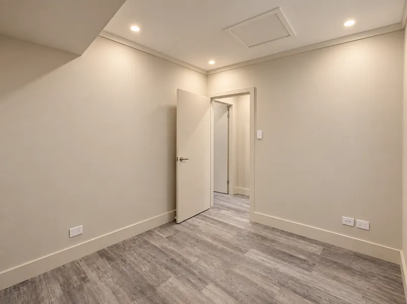 Hoxton Park garage conversion with grey timber-look flooring, an open doorway and recessed lighting