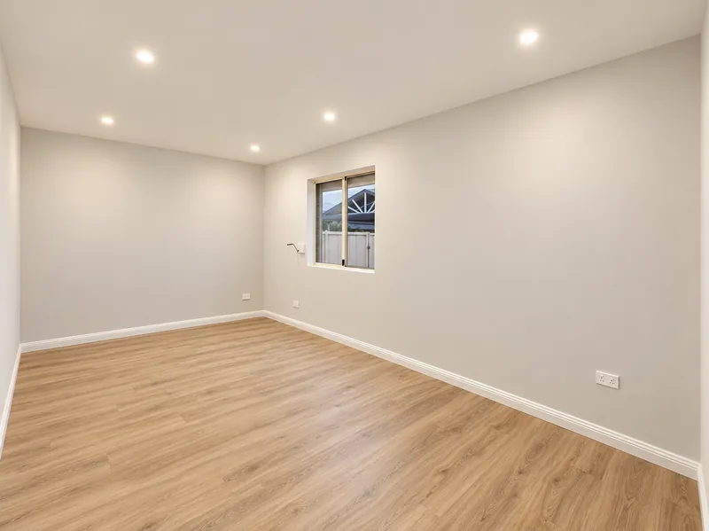 Edensor Park garage conversion with warm timber-look flooring, a window and recessed lighting