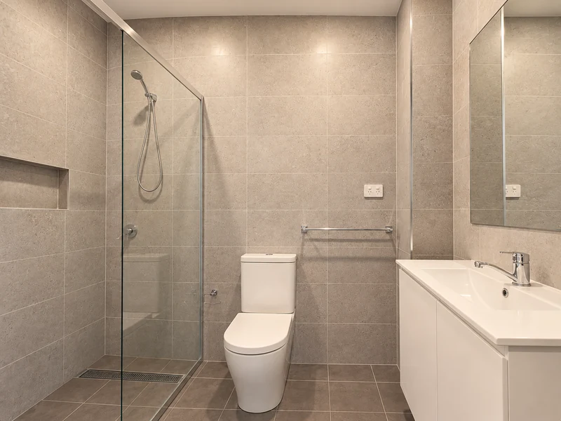 Modern bathroom with a glass shower, tiled walls and a white vanity
